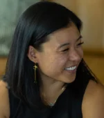 smiling woman wearing the OM Earrings-Emerald gemstone jewelry