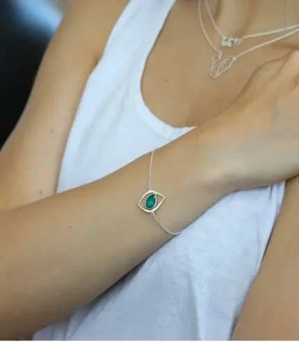 woman wearing a sterling silver bracelet in a cat eye design with a emerald stone